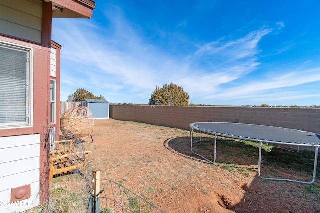 view of yard featuring a trampoline and a storage shed