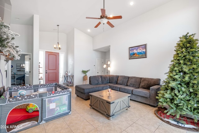 tiled living room featuring ceiling fan with notable chandelier and high vaulted ceiling