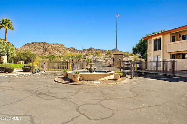 surrounding community with a gate, uncovered parking, fence, and a mountain view