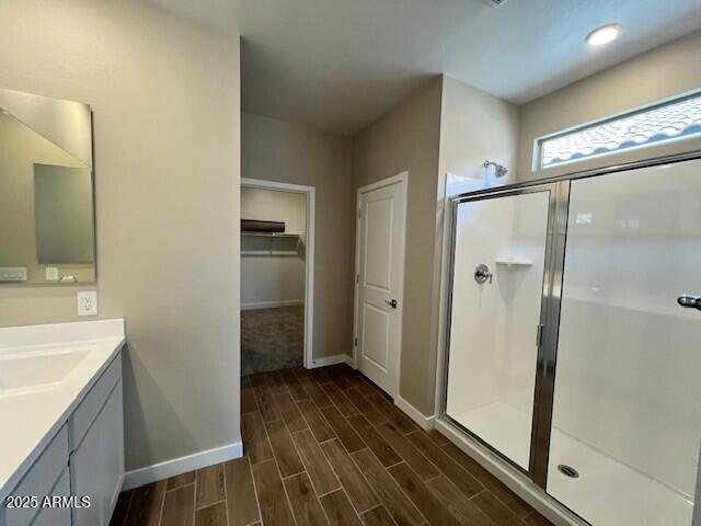2945 S 232nd Dr, Buckeye, AZ 85326 - full bathroom featuring vanity, a stall shower, wood finished floors, baseboards, and a walk in closet