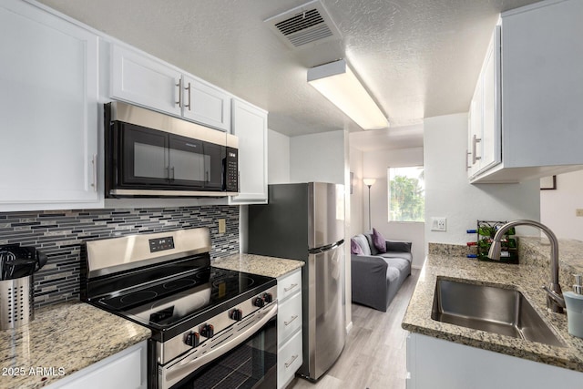 12123 W Bell Rd Unit 339, Surprise, AZ 85378 - kitchen with white cabinetry, a sink, visible vents, stainless steel appliances, and light wood-style floors