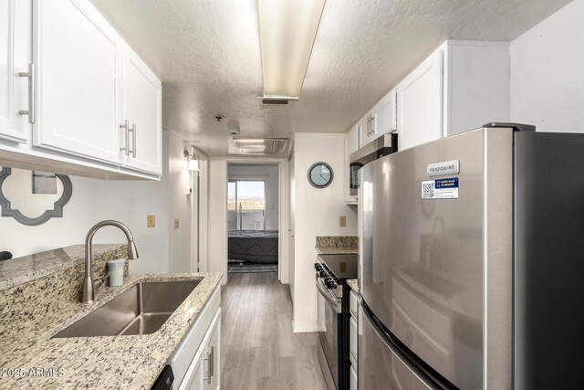 12123 W Bell Rd Unit 339, Surprise, AZ 85378 - kitchen with white cabinets, stainless steel appliances, light wood finished floors, and a sink
