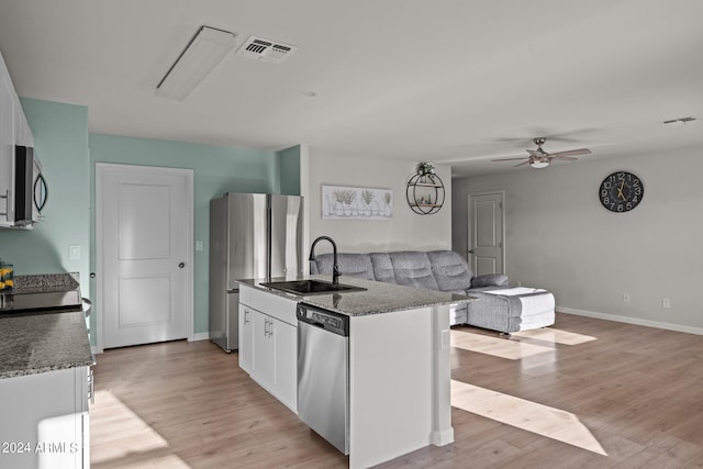 kitchen featuring appliances with stainless steel finishes, sink, white cabinets, light hardwood / wood-style floors, and an island with sink