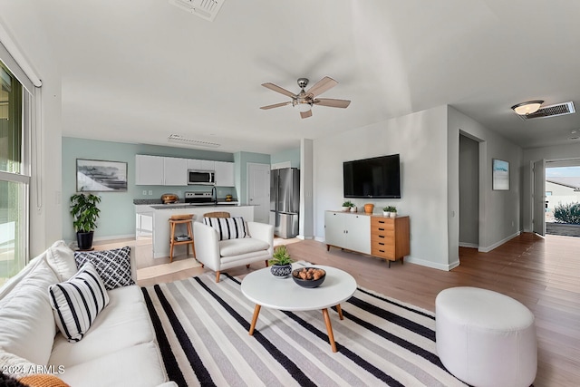 living room with ceiling fan and light wood-type flooring