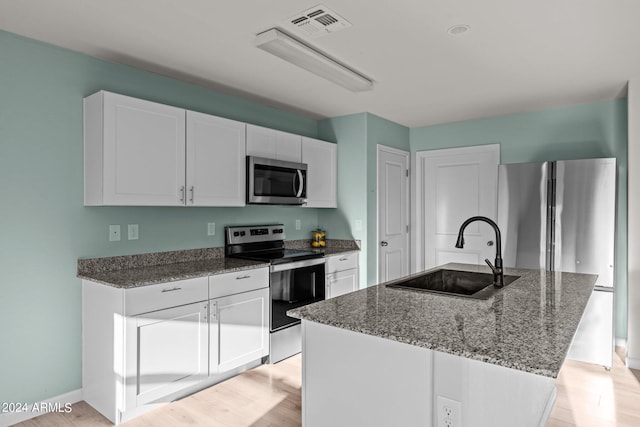 kitchen with a kitchen island with sink, sink, appliances with stainless steel finishes, light hardwood / wood-style floors, and white cabinetry