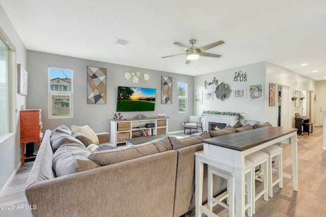 living room featuring ceiling fan, plenty of natural light, and light hardwood / wood-style floors