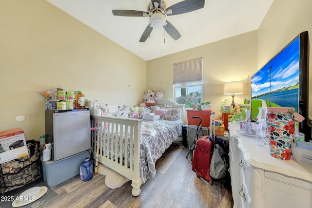 bedroom with stainless steel refrigerator, dark hardwood / wood-style floors, and ceiling fan