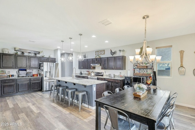 dining room with a chandelier, sink, and light hardwood / wood-style flooring