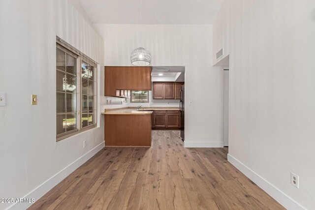 2455 E Broadway Rd Unit 39, Mesa, AZ 85204 - kitchen featuring light wood-type flooring, light countertops, a peninsula, visible vents, and freestanding refrigerator