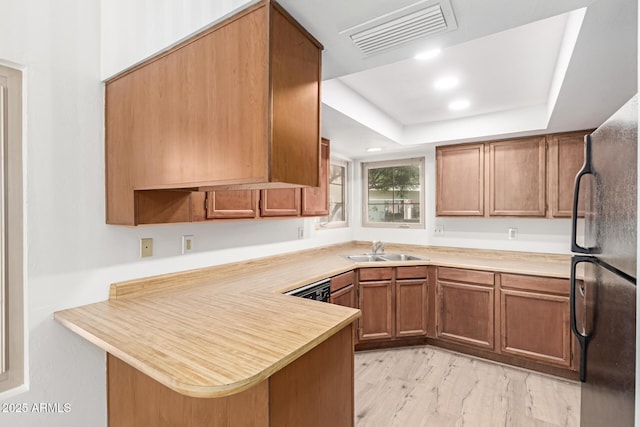 2455 E Broadway Rd Unit 39, Mesa, AZ 85204 - kitchen featuring brown cabinets, visible vents, a sink, freestanding refrigerator, and a peninsula
