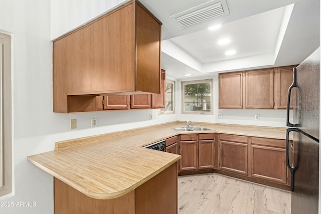 2455 E Broadway Rd Unit 39, Mesa, AZ 85204 - kitchen with visible vents, a sink, freestanding refrigerator, a peninsula, and brown cabinetry