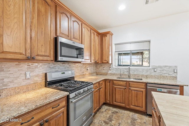 kitchen featuring light stone counters, sink, tasteful backsplash, and stainless steel appliances