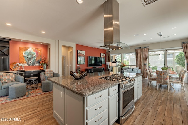 35756 N Clementine Trl, San Tan Valley, AZ 85140 - kitchen with island exhaust hood, stainless steel range with gas cooktop, light wood-style flooring, open floor plan, and white cabinetry