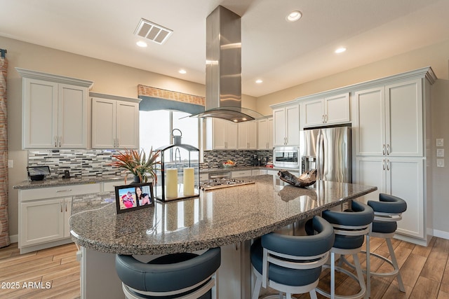 35756 N Clementine Trl, San Tan Valley, AZ 85140 - kitchen with island exhaust hood, backsplash, appliances with stainless steel finishes, and a breakfast bar