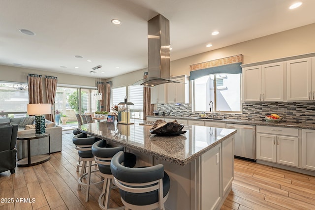 35756 N Clementine Trl, San Tan Valley, AZ 85140 - kitchen with island range hood, stainless steel dishwasher, a kitchen island, light wood-style flooring, and tasteful backsplash
