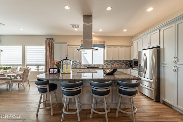 35756 N Clementine Trl, San Tan Valley, AZ 85140 - kitchen with visible vents, a center island, dark stone counters, stainless steel fridge, and a breakfast bar area