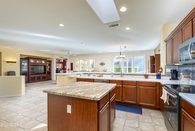 kitchen featuring kitchen peninsula, a kitchen island, stainless steel appliances, and ceiling fan with notable chandelier