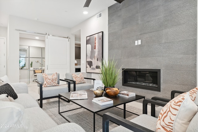 living room featuring a barn door and a large fireplace