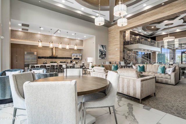 dining area featuring a towering ceiling and coffered ceiling