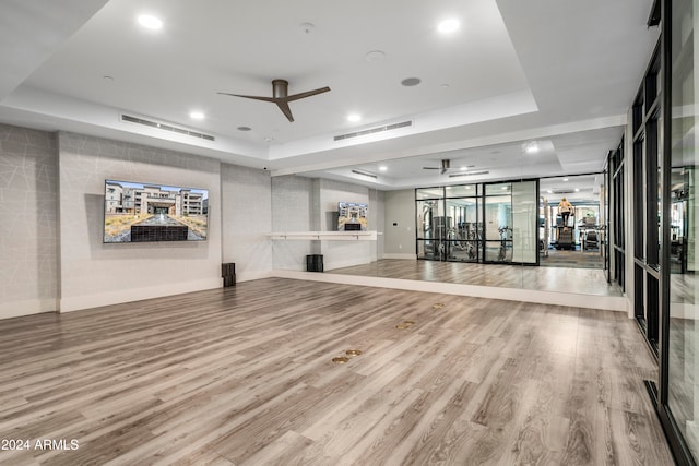 exercise area featuring wood-type flooring, a tray ceiling, and ceiling fan