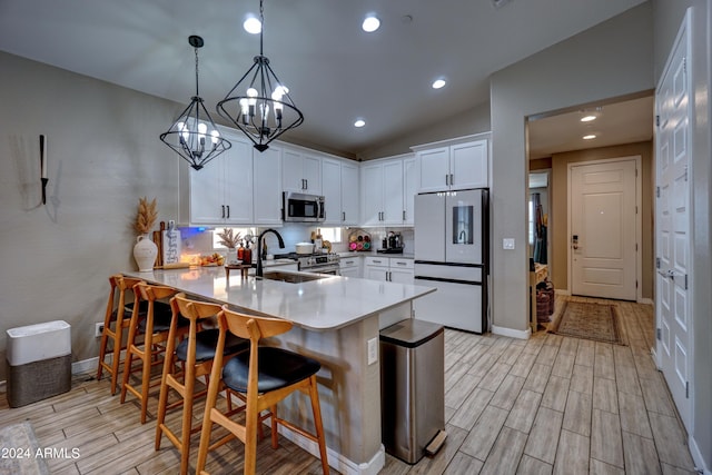 kitchen featuring white cabinets, sink, decorative light fixtures, kitchen peninsula, and stainless steel appliances