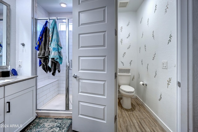 bathroom with a shower with door, vanity, hardwood / wood-style floors, and toilet