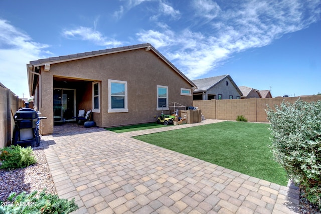 back of property with a yard and a patio