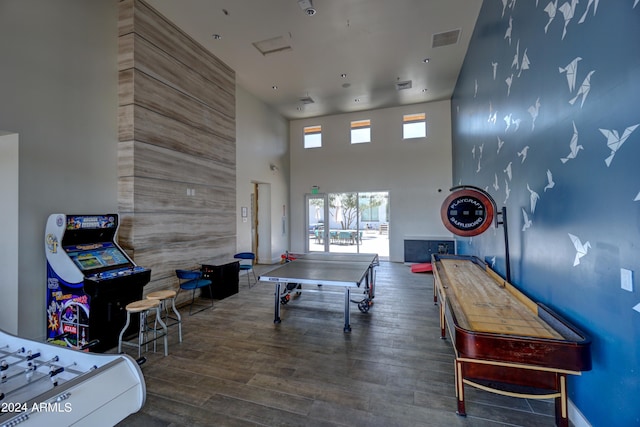 rec room featuring dark wood-type flooring and a high ceiling