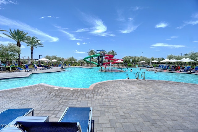 view of swimming pool featuring a water slide and a patio