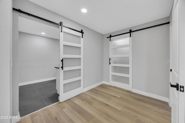 walk in closet with wood-type flooring and a barn door