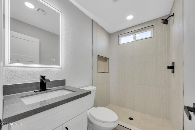 bathroom featuring vanity, toilet, and tiled shower