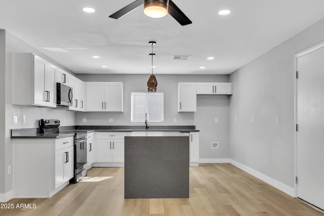 kitchen with stainless steel appliances, white cabinetry, hanging light fixtures, and a kitchen island