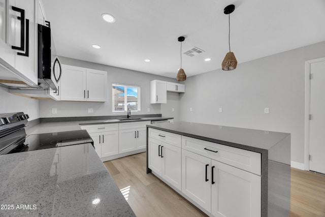 kitchen with pendant lighting, sink, black electric range, and white cabinets