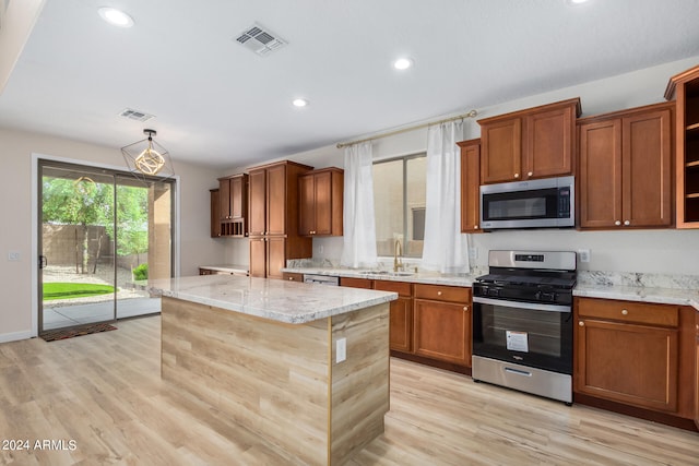 kitchen with a kitchen island, light hardwood / wood-style flooring, sink, appliances with stainless steel finishes, and light stone counters