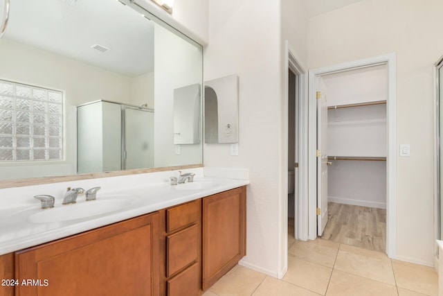 bathroom with a shower with door, vanity, and tile patterned flooring