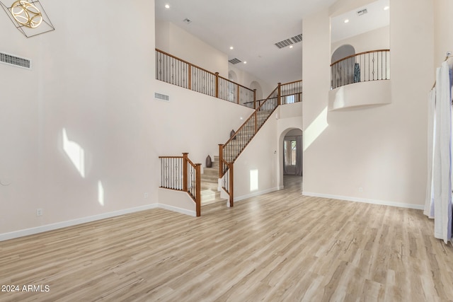 unfurnished living room featuring light hardwood / wood-style flooring and a high ceiling