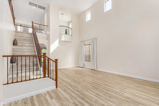 stairway featuring wood-type flooring and a high ceiling