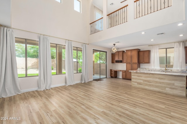 unfurnished living room featuring a towering ceiling and light hardwood / wood-style floors