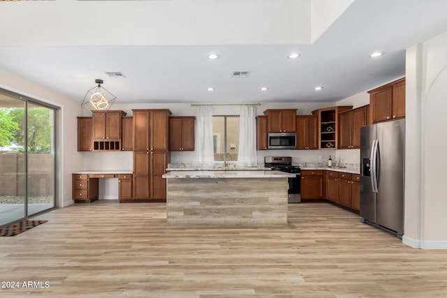 kitchen with appliances with stainless steel finishes, light hardwood / wood-style flooring, a kitchen island, and pendant lighting