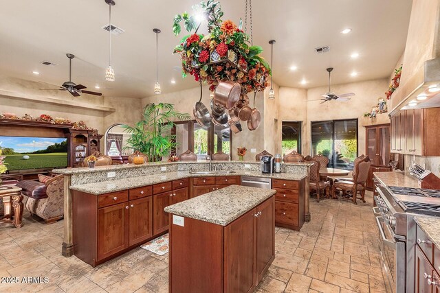 kitchen with stainless steel appliances, a towering ceiling, custom range hood, ceiling fan, and a kitchen island