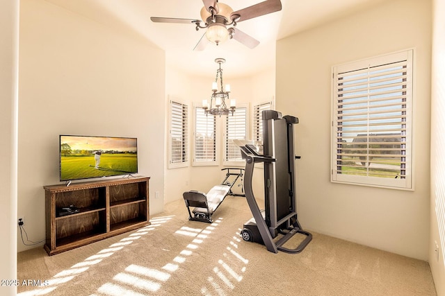 workout room with ceiling fan with notable chandelier and light carpet