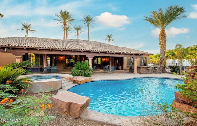 view of swimming pool featuring a bar, a patio area, and an in ground hot tub