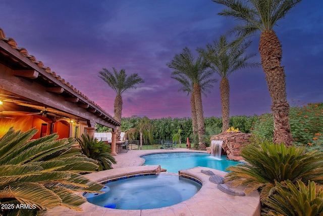 pool at dusk featuring an in ground hot tub