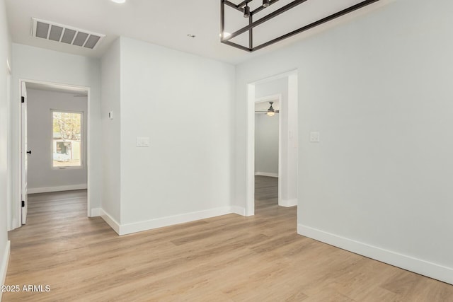 empty room featuring light wood finished floors, visible vents, a ceiling fan, and baseboards