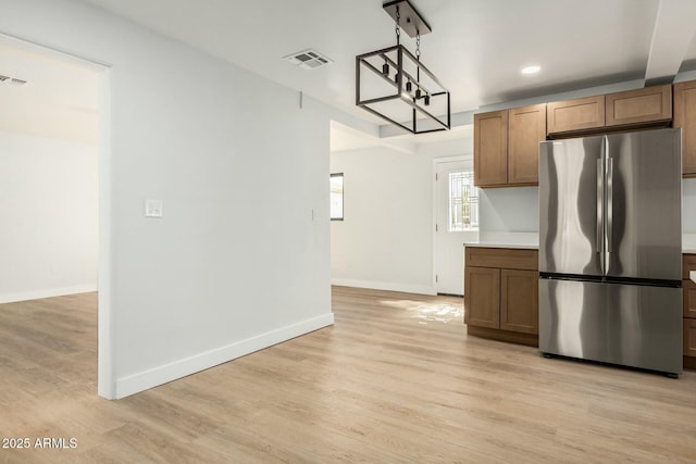 kitchen with visible vents, baseboards, decorative light fixtures, light wood-style flooring, and freestanding refrigerator