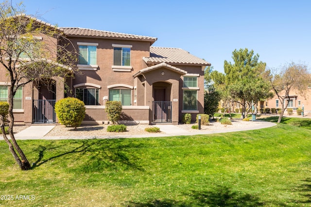 exterior space with a tiled roof, a yard, a fenced front yard, and stucco siding