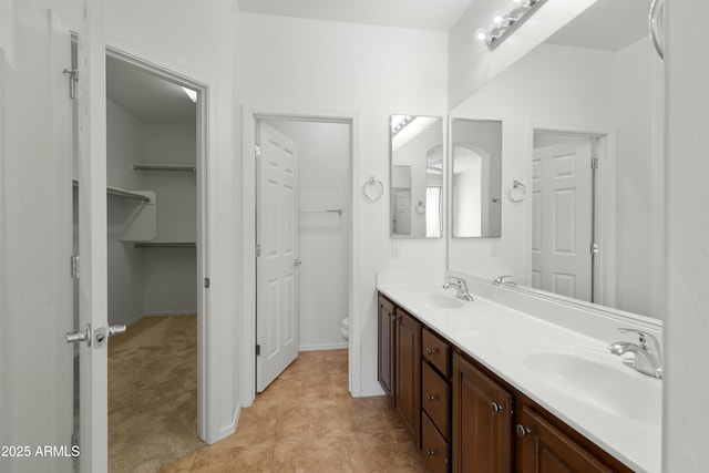 full bath with toilet, tile patterned flooring, double vanity, and a sink