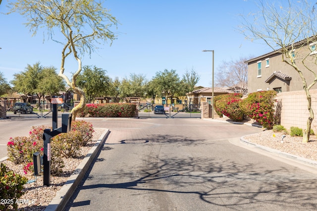 view of street with a gate, curbs, and a gated entry