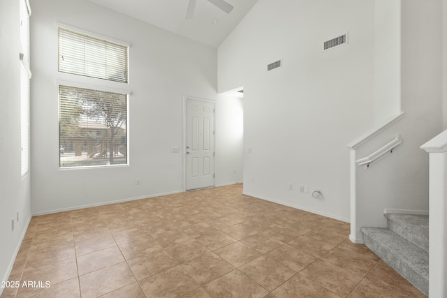 spare room featuring a ceiling fan, visible vents, high vaulted ceiling, and stairs