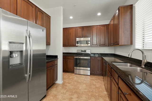 kitchen featuring dark stone counters, stainless steel appliances, a sink, and recessed lighting